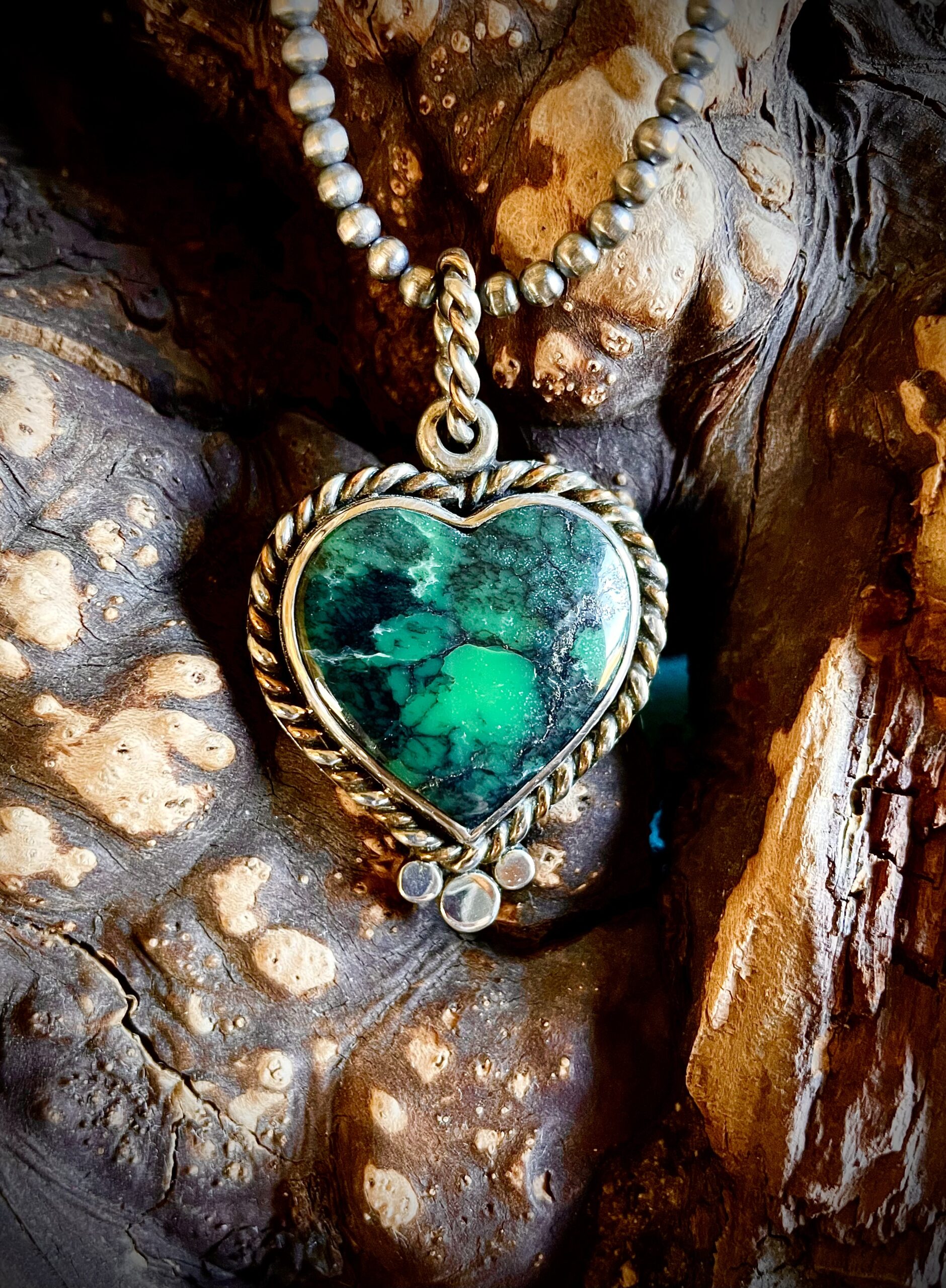 A heart-shaped turquoise pendant with intricate gold detailing.